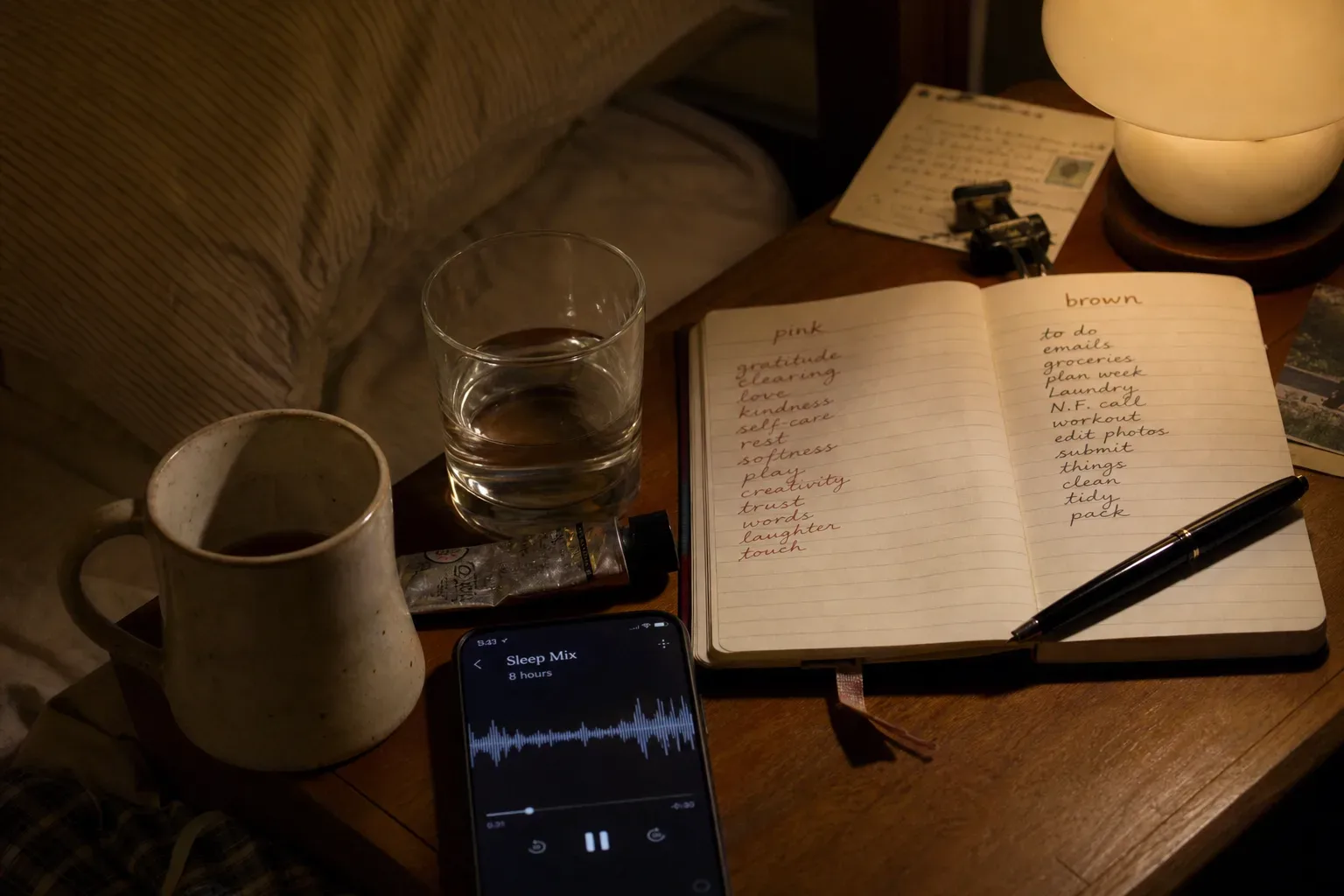 Telefono che riproduce audio per il sonno accanto a una lampada da comodino soffusa