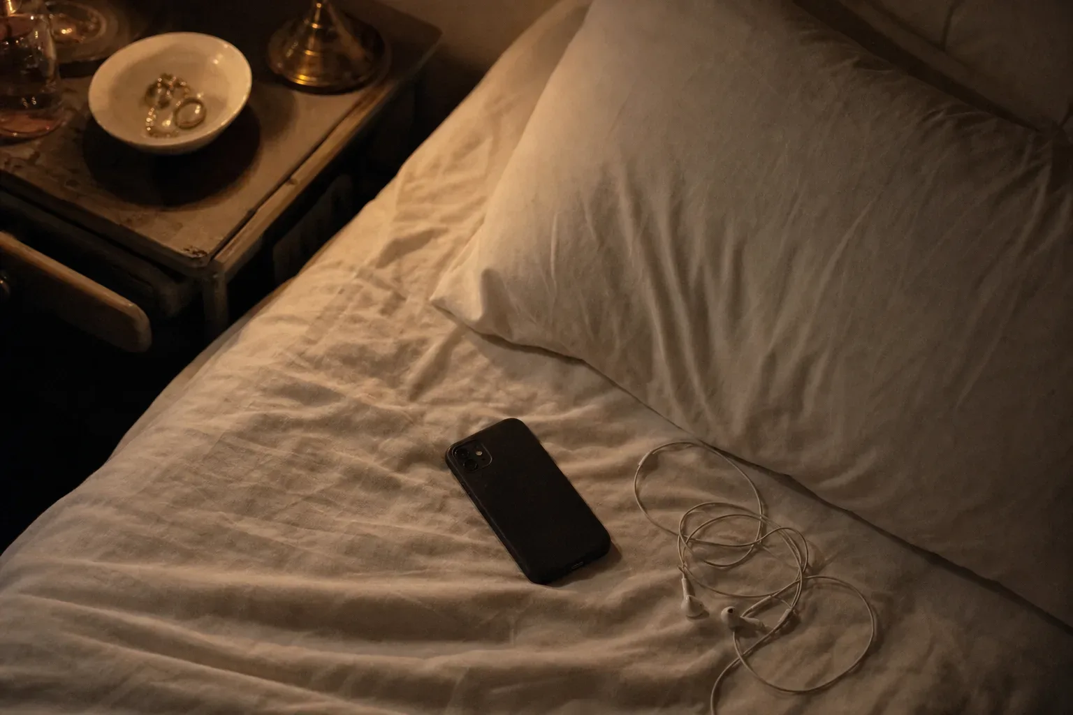 Gece yatak yanında kulaklıklarla duran telefon